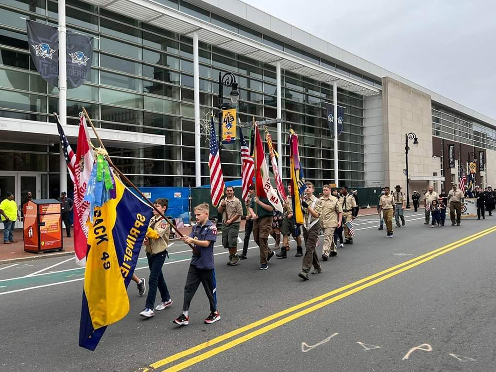 Boy Scouts walking in a parade with flags